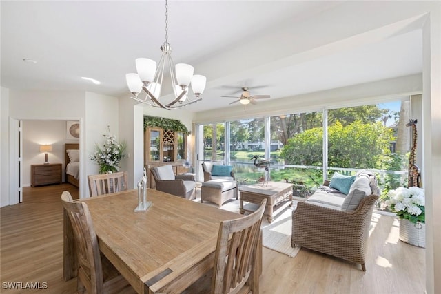 dining room with ceiling fan with notable chandelier and light hardwood / wood-style floors