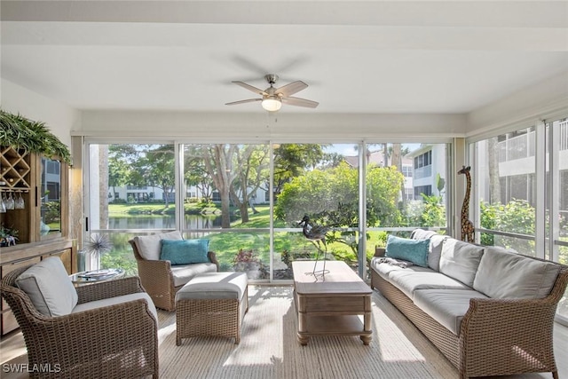 sunroom with a healthy amount of sunlight, a water view, and ceiling fan