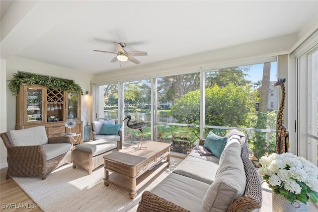 sunroom / solarium with ceiling fan and a water view