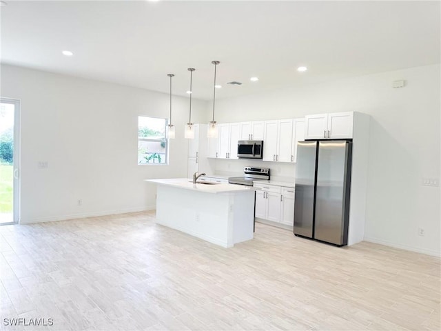 kitchen with a kitchen island with sink, sink, appliances with stainless steel finishes, decorative light fixtures, and white cabinetry