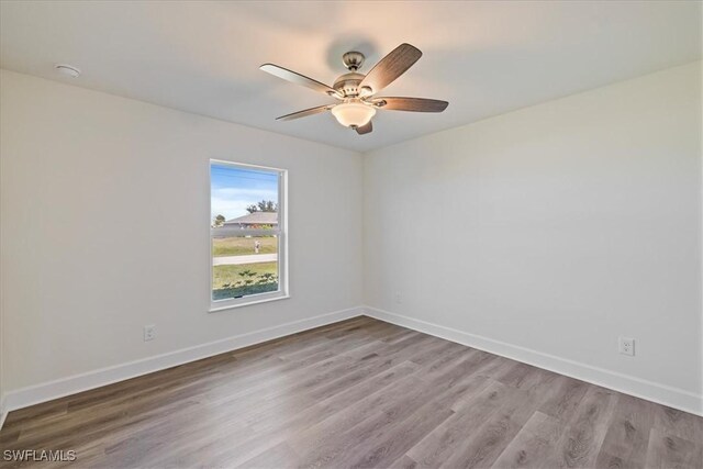 spare room with a ceiling fan, wood finished floors, and baseboards