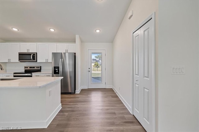 kitchen featuring wood finished floors, recessed lighting, appliances with stainless steel finishes, white cabinets, and light countertops