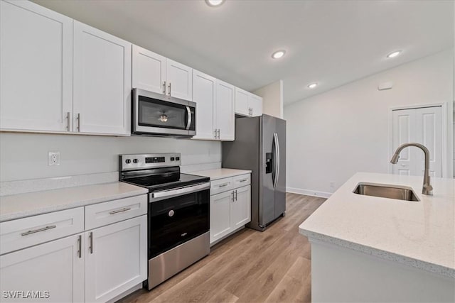 kitchen featuring recessed lighting, appliances with stainless steel finishes, light wood-style floors, white cabinetry, and a sink