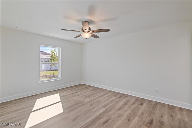 unfurnished room with a ceiling fan, light wood-type flooring, and baseboards