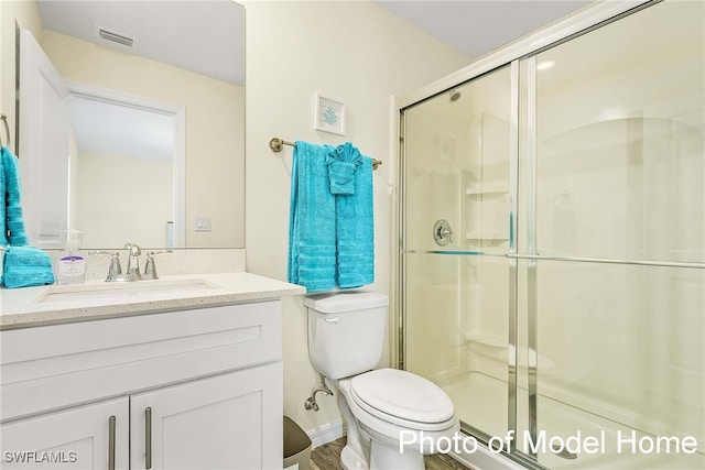 bathroom with visible vents, a shower stall, toilet, and vanity