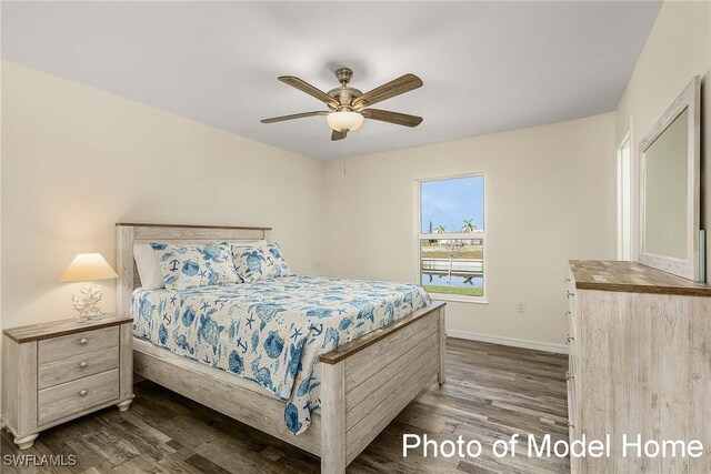 bedroom with ceiling fan, dark wood-type flooring, and baseboards