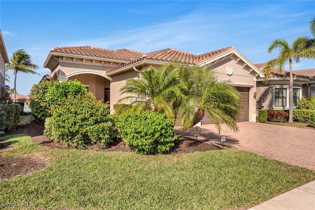 mediterranean / spanish home featuring a garage and a front yard