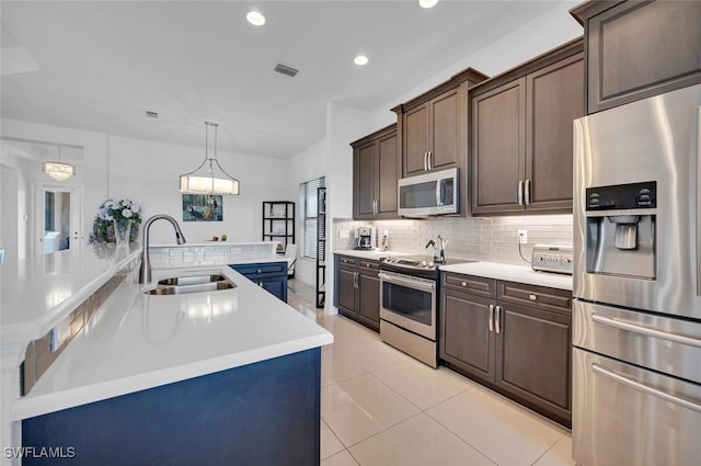 kitchen featuring pendant lighting, sink, stainless steel appliances, and dark brown cabinetry