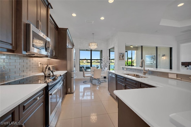 kitchen featuring light tile patterned flooring, dark brown cabinetry, sink, pendant lighting, and stainless steel appliances