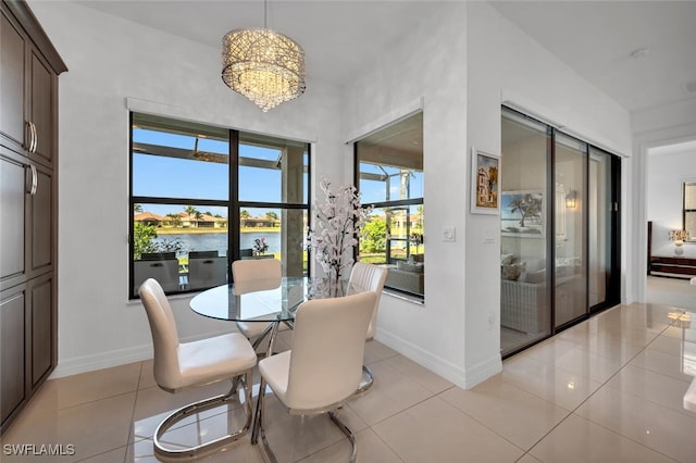 tiled dining room featuring a notable chandelier and a water view