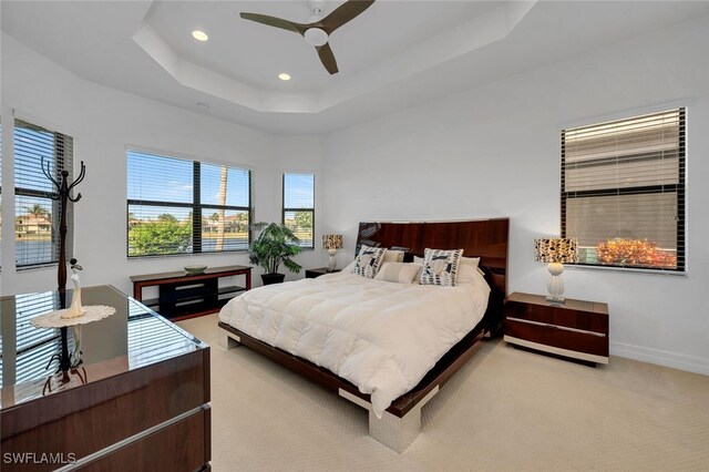 bedroom featuring ceiling fan, a tray ceiling, and carpet flooring