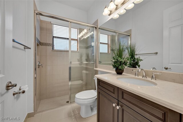 bathroom featuring a shower with shower door, toilet, vanity, and tile patterned flooring