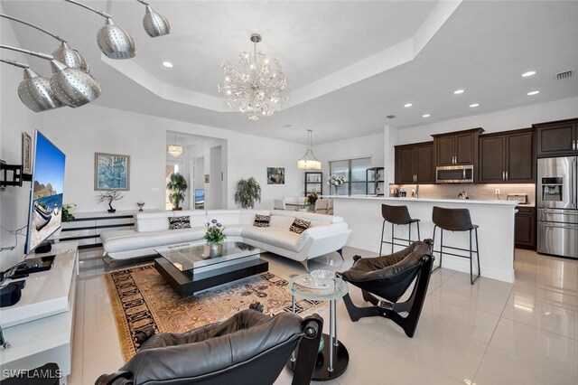 tiled living room with an inviting chandelier and a tray ceiling