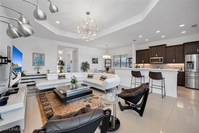 tiled living room with an inviting chandelier and a tray ceiling