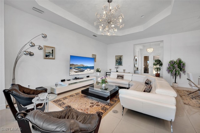 tiled living room featuring french doors, a raised ceiling, and a notable chandelier