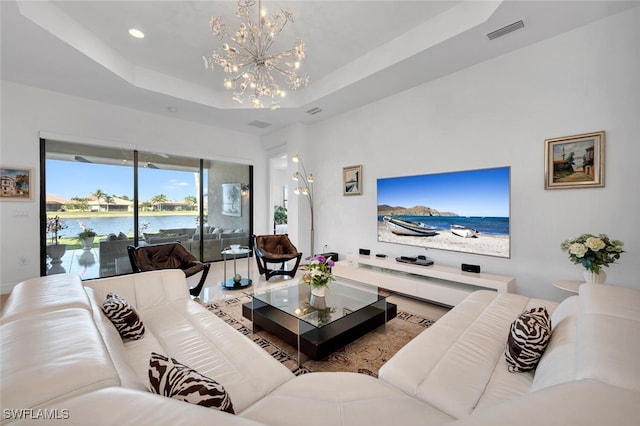 living room featuring a chandelier, a raised ceiling, and a water view