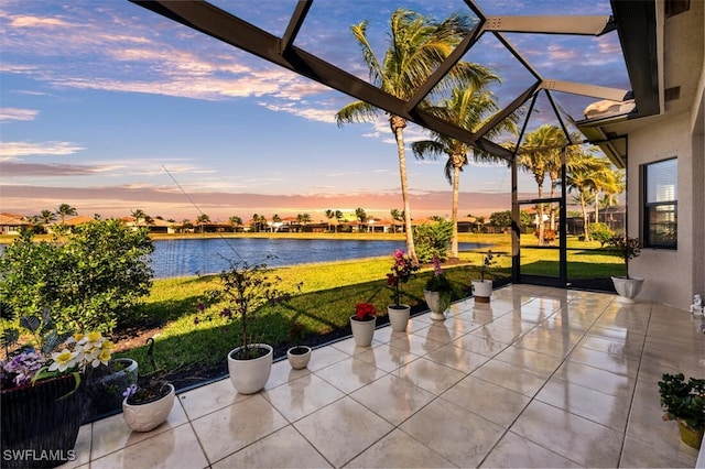 exterior space featuring a lanai, a lawn, and a water view