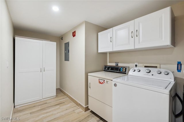 washroom with light wood finished floors, cabinet space, washing machine and dryer, electric panel, and baseboards