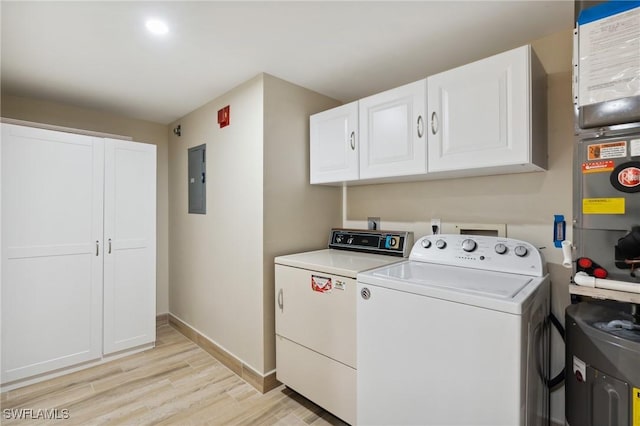 clothes washing area featuring baseboards, independent washer and dryer, electric panel, cabinet space, and light wood finished floors