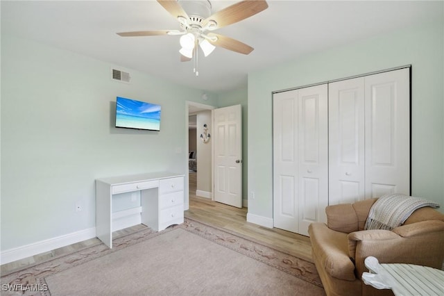 living area with light wood-style floors, baseboards, visible vents, and ceiling fan