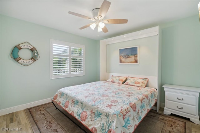 bedroom with wood finished floors, a ceiling fan, and baseboards