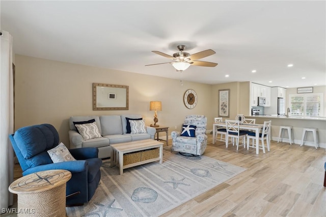 living area featuring light wood-type flooring, ceiling fan, baseboards, and recessed lighting