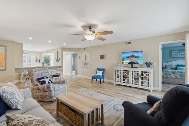 living room featuring baseboards, light wood-style flooring, visible vents, and recessed lighting