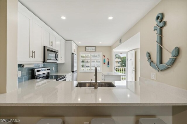 kitchen with sink, white cabinets, appliances with stainless steel finishes, and kitchen peninsula