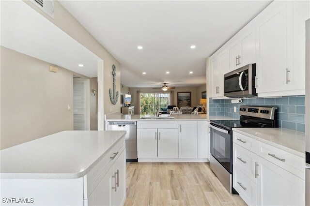 kitchen featuring kitchen peninsula, ceiling fan, appliances with stainless steel finishes, tasteful backsplash, and white cabinets