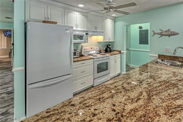 kitchen featuring white appliances, white cabinetry, a sink, and under cabinet range hood