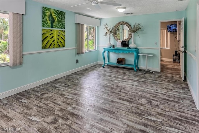 empty room featuring visible vents, a textured ceiling, baseboards, and wood finished floors