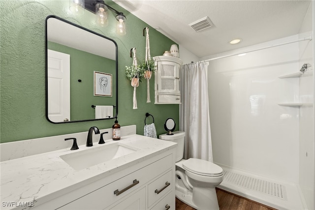 bathroom featuring a shower with shower curtain, a textured ceiling, toilet, vanity, and hardwood / wood-style flooring