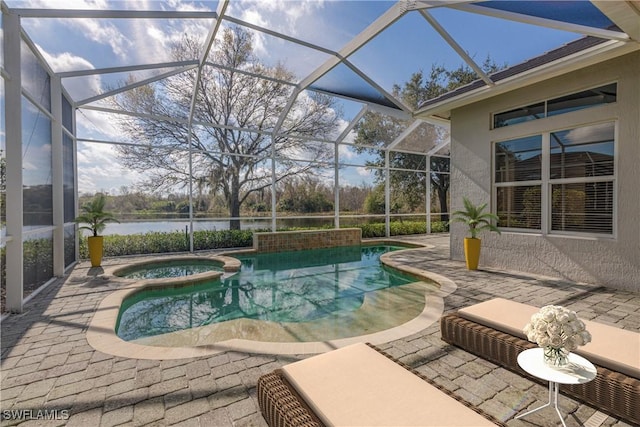 view of pool with an in ground hot tub, a water view, glass enclosure, and a patio area