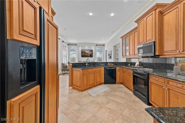 kitchen featuring dark stone counters, black appliances, sink, crown molding, and kitchen peninsula