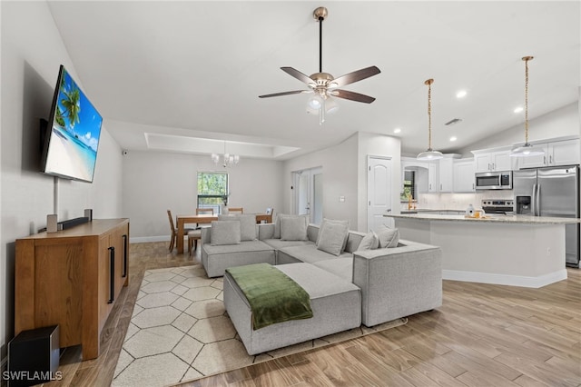 living room with ceiling fan with notable chandelier and light hardwood / wood-style floors