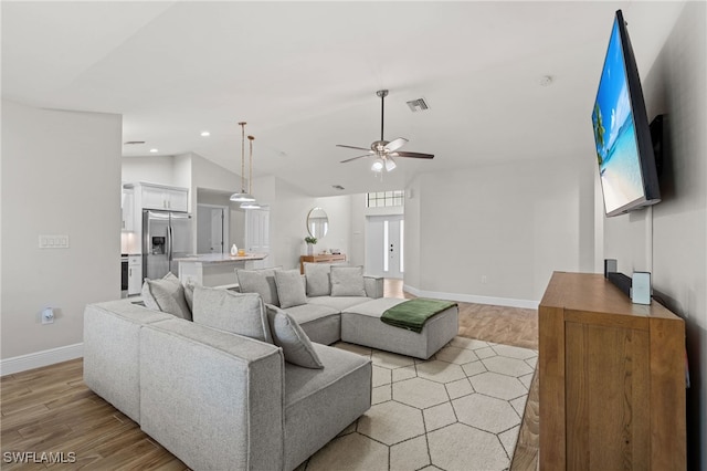 living room with ceiling fan, light hardwood / wood-style floors, french doors, and vaulted ceiling