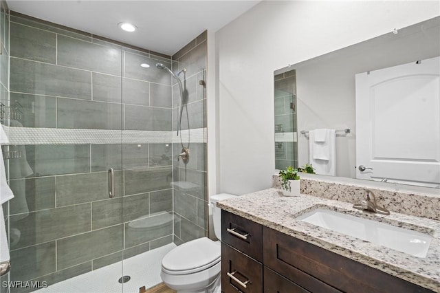 bathroom featuring vanity, toilet, and a shower with door