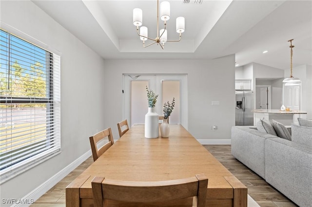 dining area featuring light hardwood / wood-style floors, french doors, and an inviting chandelier