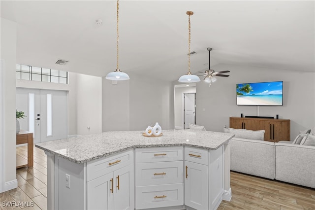 kitchen with ceiling fan, white cabinets, pendant lighting, and a kitchen island