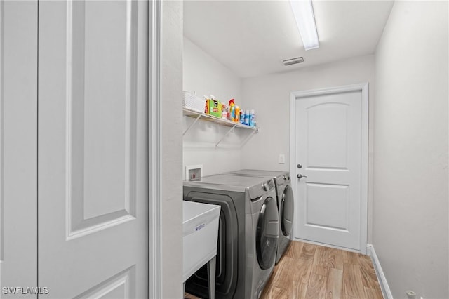 laundry room featuring washer and dryer and light wood-type flooring