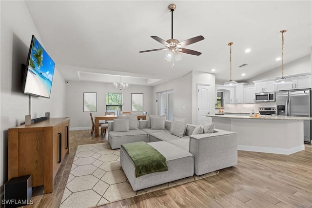 living room featuring ceiling fan with notable chandelier and light hardwood / wood-style floors