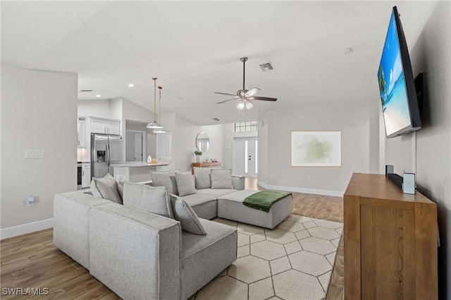 living room with ceiling fan, light hardwood / wood-style floors, and lofted ceiling