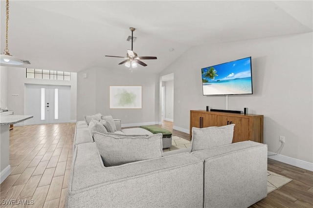 living room with ceiling fan, wood-type flooring, and vaulted ceiling