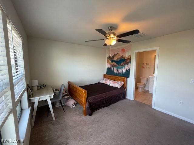 carpeted bedroom with ceiling fan and ensuite bath