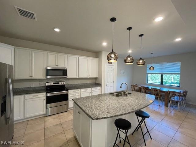 kitchen featuring appliances with stainless steel finishes, a kitchen island with sink, sink, pendant lighting, and white cabinetry