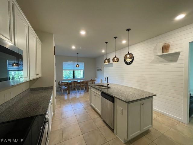 kitchen with pendant lighting, a center island with sink, sink, white cabinetry, and stainless steel appliances