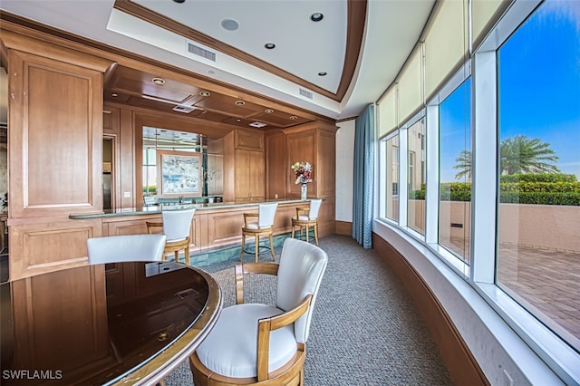 carpeted dining room featuring a tray ceiling and crown molding