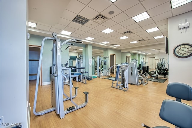 gym with light wood-type flooring and a paneled ceiling