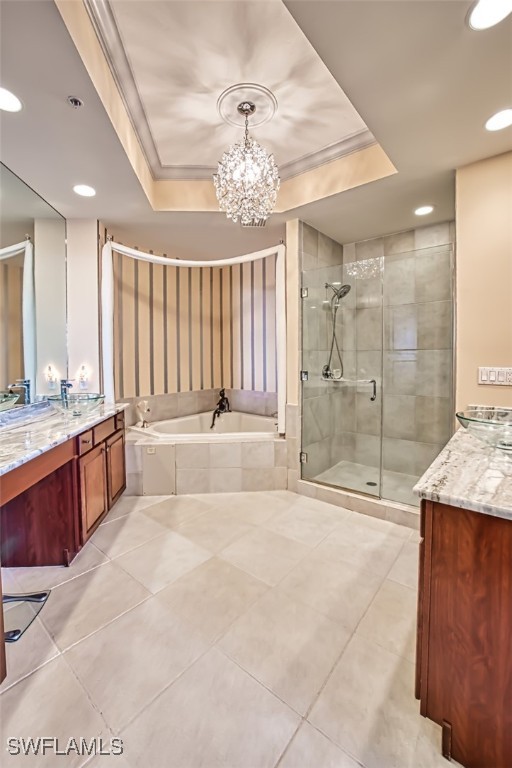 bathroom featuring a tray ceiling, vanity, plus walk in shower, and ornamental molding