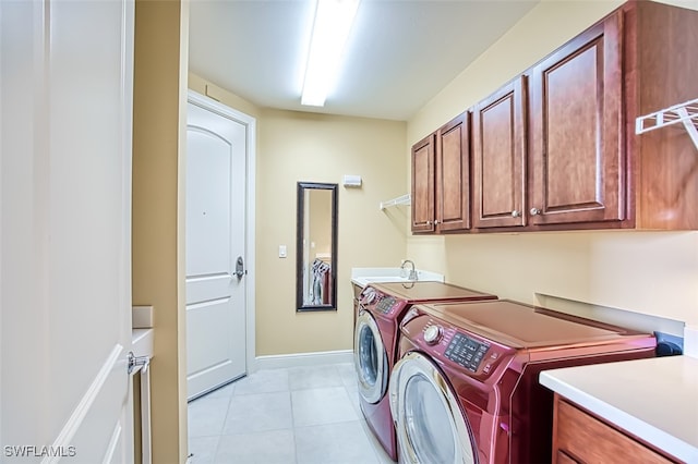 clothes washing area with cabinets, light tile patterned floors, washing machine and dryer, and sink